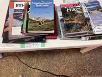 Photo showing a variety of hiking and trail guidebooks including The Canadian Rockies Trail Guide, 103 Hikes in North America, and other destination-specific guides mainly related to North America and Canada