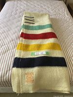 Full folded blanket on striped bedcover showing stripe configuration and overall size