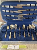 Full view of original blue velvet-lined case containing multiple silver plated utensils including knives, forks, and spoons.
