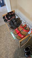 Three pairs of women's sandals displayed on a shelf: red flower-decorated, black broad-strapped, and multi-color sporty style, all size 7.5.
