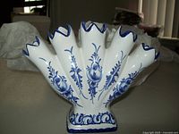 Front side view of the antique hand painted fan shaped bud vase showing five blue and white floral decorated tubes and the base