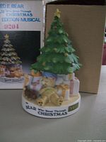Photo of limited edition Ted E. Bear musical Christmas tree with a sleeping bear figurine and presents, alongside its original box.