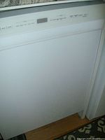 Front view of the white dishwasher with visible front control panel and door closed.