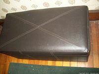 Top view of brown faux leather ottoman showing stitched 'X' design on top.