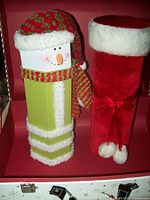 Front view of green snowman wine box and red Christmas stocking wine box inside suitcase