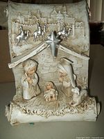 Front view of the one-piece nativity scene showing Mary, Joseph, baby Jesus, lamb, star, and cityscape backdrop in a textured stable.