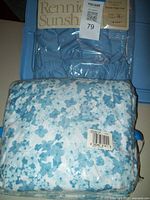 Photo showing folded queen size sheet set in packaging with blue floral pattern and brand label Rennie Sunshine visible