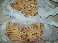 Two plastic bags filled with natural wood-colored clothespins, showing the contents clearly and the quantity in each bag.