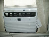 Frigidaire window air conditioner installed in window, showing front control panel and vents.