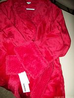 Close-up of the red fleece robe showing plush collar, sleeve cuff, and brand tag Sonoma.