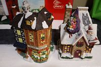 Overall view of two Christmas village houses showing Village Grocery and Santa decorated house with snow-covered roofs