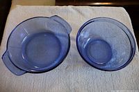 Two cobalt blue Pyrex mixing bowls shown on a white towel, one with handles and a spout (2.5 quart), the other a round bowl (2 quart).