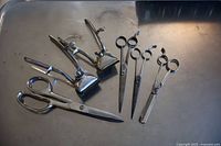 Overview photo showing 4 scissors and 2 manual hair clippers arranged on a metal surface.