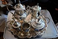 Overview of the 7-piece silver plate tea set arranged on a large ornate silver tray, showing all included items.