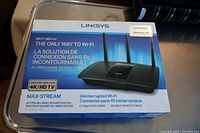 Photo of box front showing Linksys Max-Stream router with features and specifications such as 4K/HD TV support, 1.7Gbps dual-band speed, and MU-MIMO technology.
