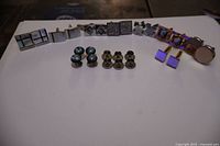 Wide view of eight pairs of cufflinks arranged in a row with two sets of studs placed in front. Several cufflinks feature Mother of Pearl or crystal details