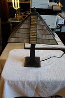 Front view of Art Deco slag glass lamp on white cloth, showing pyramid shade and square metal base.