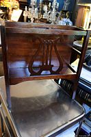 Side view showing lyre cutout on the mahogany magazine rack and solid wood build.