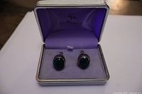 Pair of sterling silver cufflinks with dark green oval stones in purple fabric-lined case labeled Cuffwear