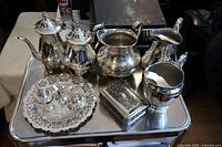 Full set on silver tray showing two tea pots, water jug, creamer, sugar bowl, jewelry box, and candle holders