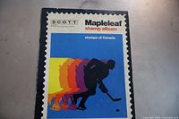 Front cover of the vintage Scott Maple Leaf stamp album showing a hockey player in silhouette and vibrant colors.