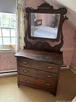 Full view of antique wooden dresser with attached mirror, showing overall structure and condition.