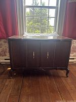 Front view of antique French Provincial server cabinet showing two folding doors and scrolled feet.