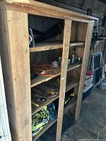 Wide angled side view of the antique pine bookcase cabinet showing natural wood with visible wear and four shelves holding various small items and tools.