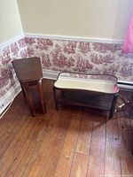 Photo of the two tables showing the mirrored table with reflective surface and dark frame, next to the retro mid century wooden table with tapered legs and lower shelf.