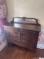 Front view of oak sideboard with mirrored backsplash, two drawers, two doors, lower drawer, and cabriole legs