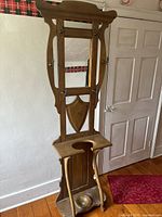 Full view of the tall wooden umbrella stand with coat hooks, mirror, and umbrella holder