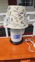 Full view of the Asian style table lamp showing white ceramic tea pot base and embroidered fabric shade