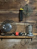 Various metal and plastic bird feeders including round cages, wire swan feeder, and tubular feeder hung on wall