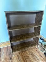 Front view of bookshelf showing three shelves and wood grain finish.