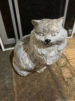 Front view of cement cat garden statue placed on outdoor surface showing detailed face and fur texture.