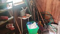 Wooden handled garden tools, wheelbarrow, gloves, and cloth seen inside shed corner