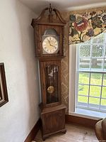 Full view of tall wooden grandfather clock in room corner