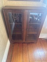 Full front view of vintage glass front bookcase with two doors and wooden knobs.