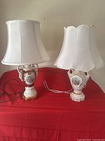 Full view of two matching porcelain table lamps with white fabric shades showing size and condition