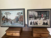 Both framed paintings side by side on wooden surface