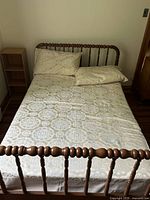 Top view of full bed with mattress and bedding, showing headboard and footboard with spool spindle design.