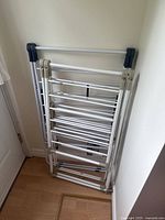 Folding drying racks folded and leaning against the wall in an indoor space.