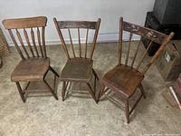 Three wooden chairs arranged side by side facing forward showing different back styles and overall wear.