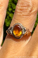 Close-up photo of the ring showing the oval citrine set in a 10k gold band with floral accents.