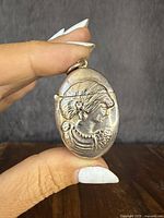 Front view showing embossed female profile in high relief with detailed hair and accessories.