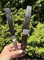 Two antique sterling silver letter openers held showing full length, blades and tortoiseshell handles