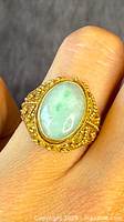 Close-up front view of ring showing oval jade cabochon and detailed filigree