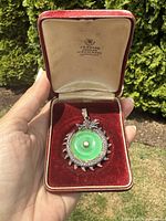 Pendant displayed in open red velvet jeweler box with ivory satin lid interior