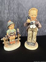Both Hummel figurines displayed side by side showing full figures