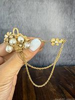 Front view showing floral cluster of leaves, flowers and faux pearls with dual chain drape